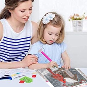 Woman and child doing a cardinal diamond painting kit at a table, with a partially completed artwork in the foreground.