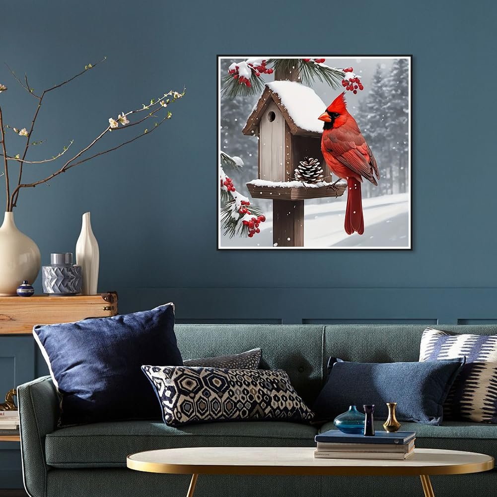 Diamond painting of a cardinal on a snowy birdhouse, displayed on a wall above a sofa.