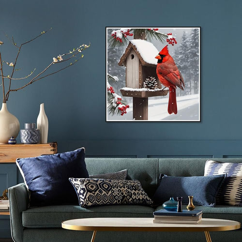 Diamond painting of a cardinal on a snowy birdhouse, displayed on a wall above a sofa.