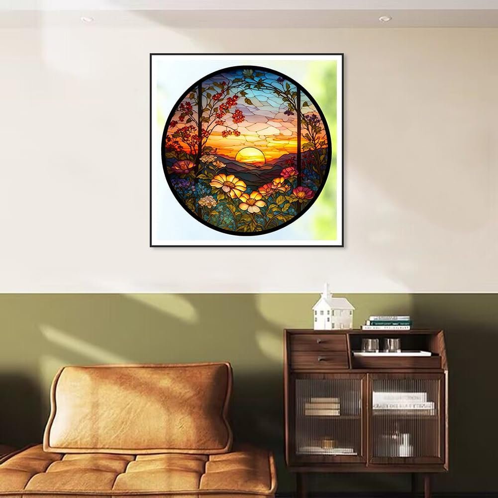 Circular stained glass art of a sunset over mountains with flowers in the foreground, framed and hung on a wall.