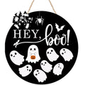 Round black Halloween door sign with 'Hey Boo' text and ghost graphics, topped with a bow and hanging spider.