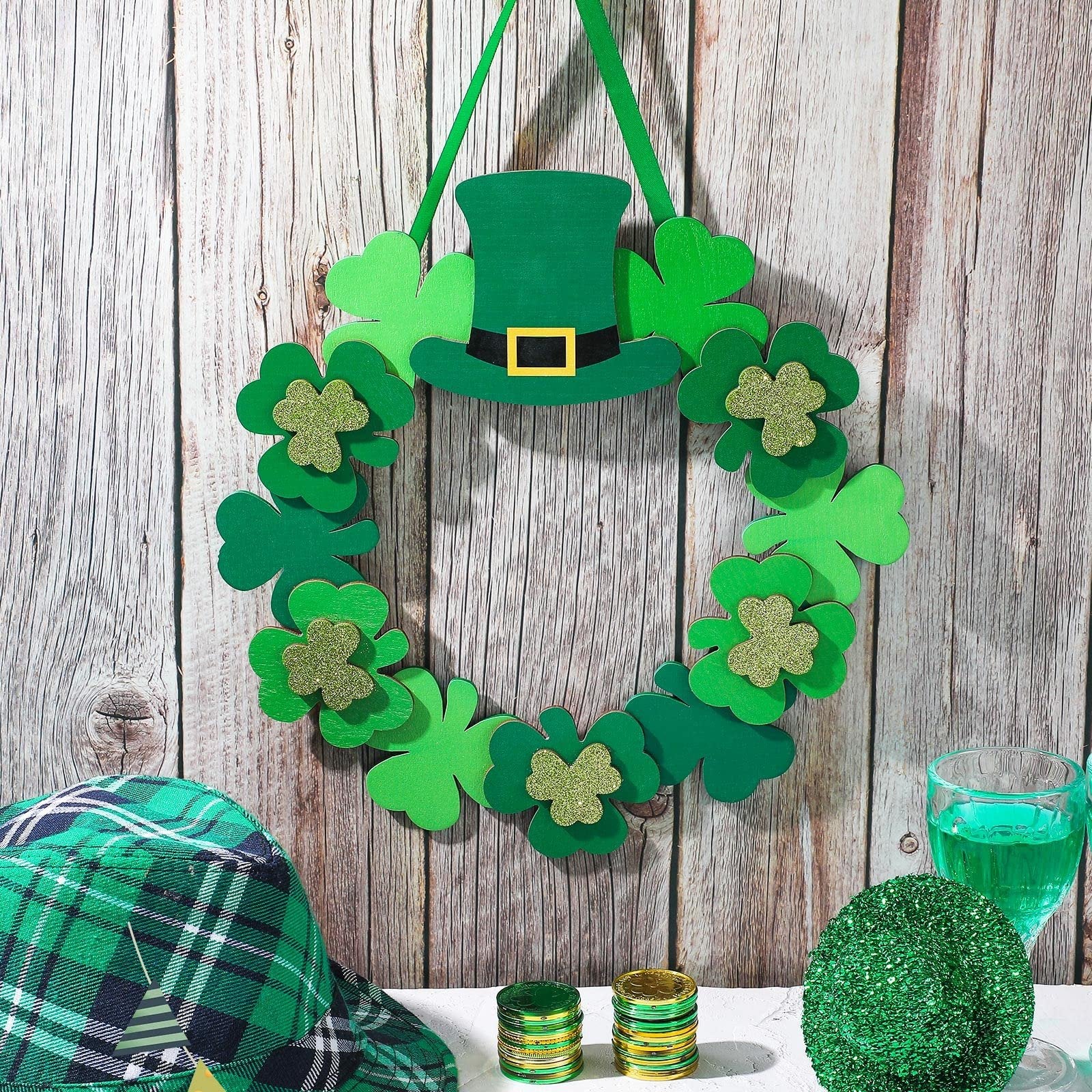St. Patrick's Day wreath with shamrocks and a leprechaun hat, displayed with a plaid hat, gold coins, and a green drink.
