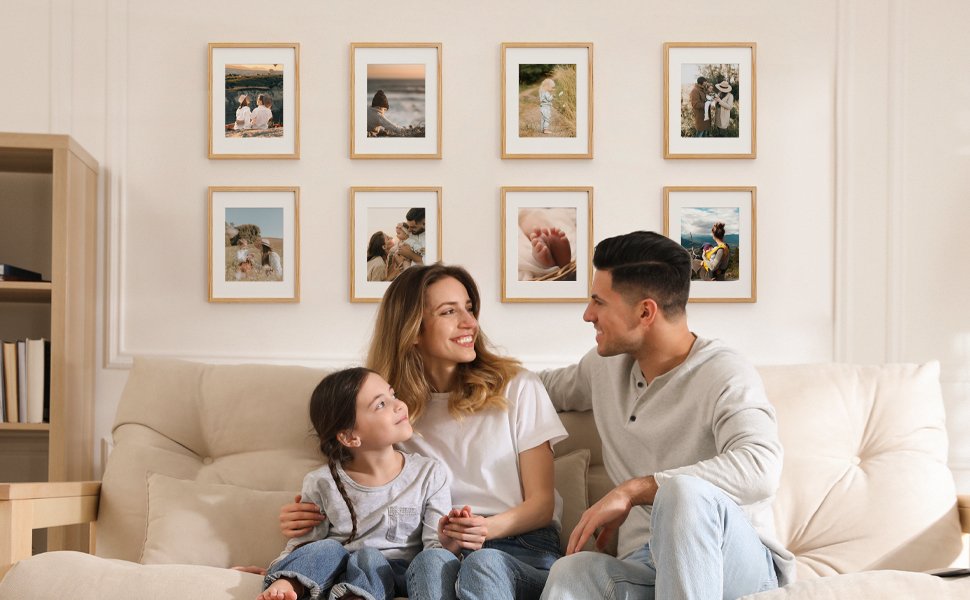 Family of three sitting on a couch looking at framed photos on the wall