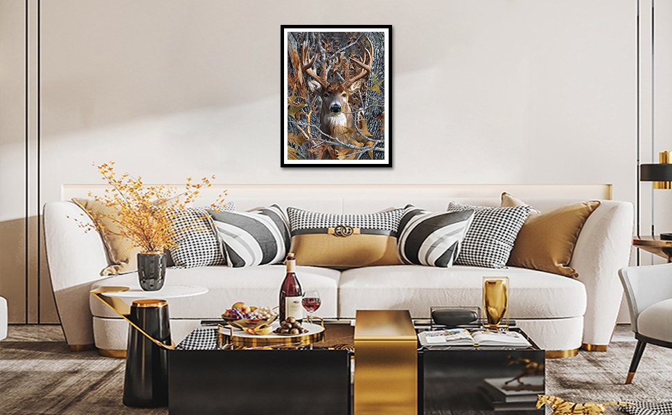 Framed 5D diamond art painting of a deer in a forest setting hanging above a sofa.