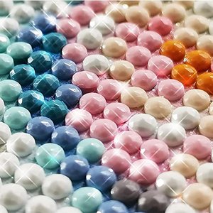 Close-up of colorful resin diamonds for a 5D diamond art painting kit, arranged in rows.