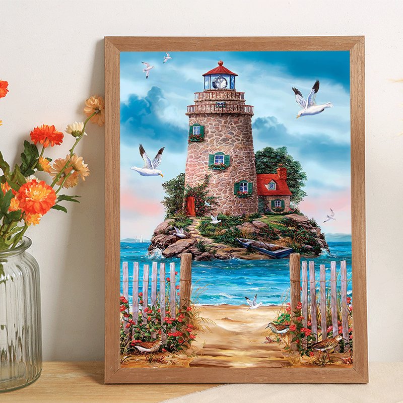 Diamond painting kit showing a lighthouse on a rocky island with seagulls flying around it, a beach in the foreground, and a wooden frame.