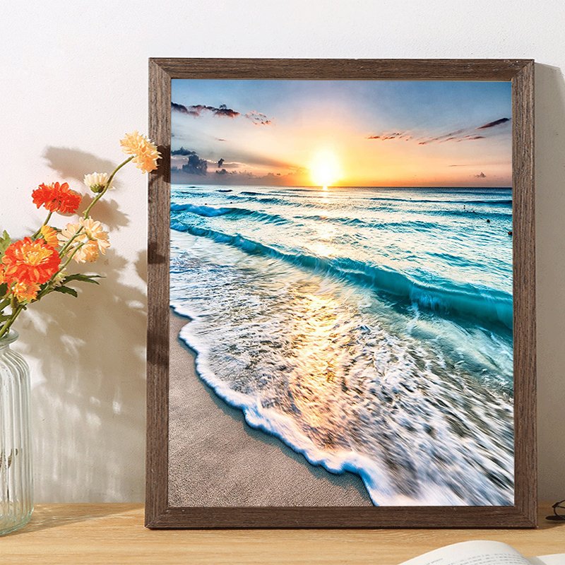 Framed 5D diamond painting kit showing a serene beach sunset with waves crashing on the shore.