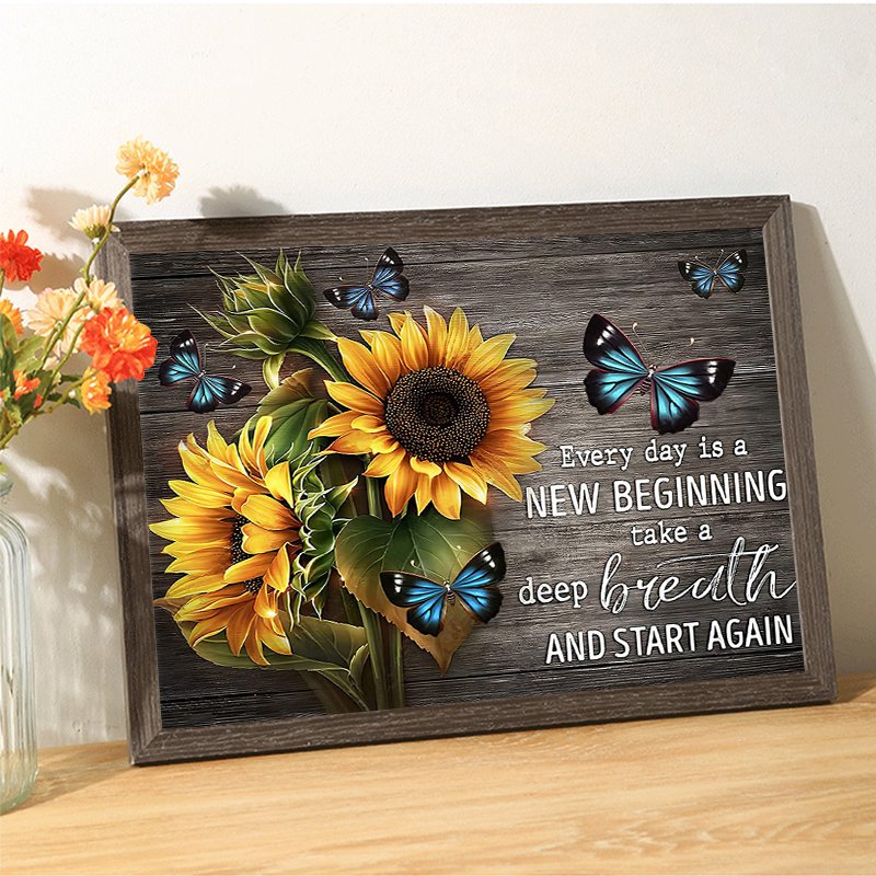 Framed sunflower and butterfly artwork with inspirational quote on a wooden background.