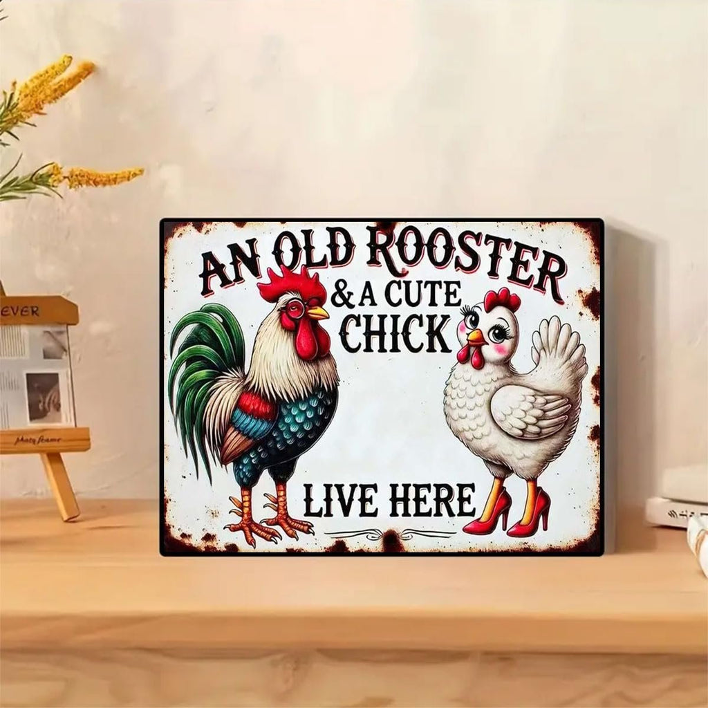 Metal sign with illustration of a rooster and a hen wearing high heels, text reads 'AN OLD ROOSTER & A CUTE CHICK LIVE HERE'.