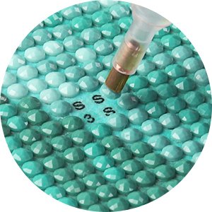 Close-up of diamond painting canvas with round resin diamonds and applicator tool, showing grid symbols S3.
