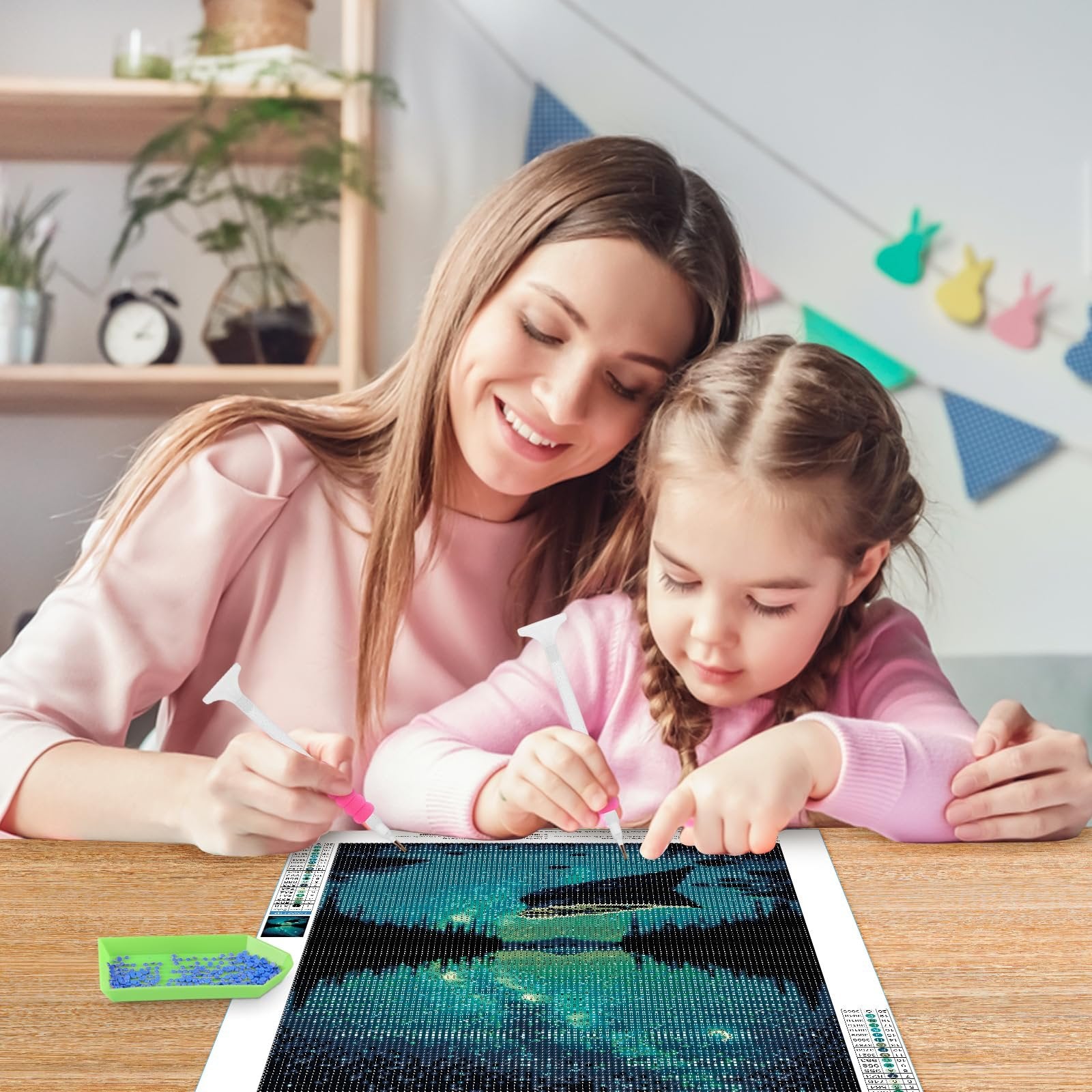 Mother and daughter doing a diamond painting kit of a starry night canoe lake landscape.