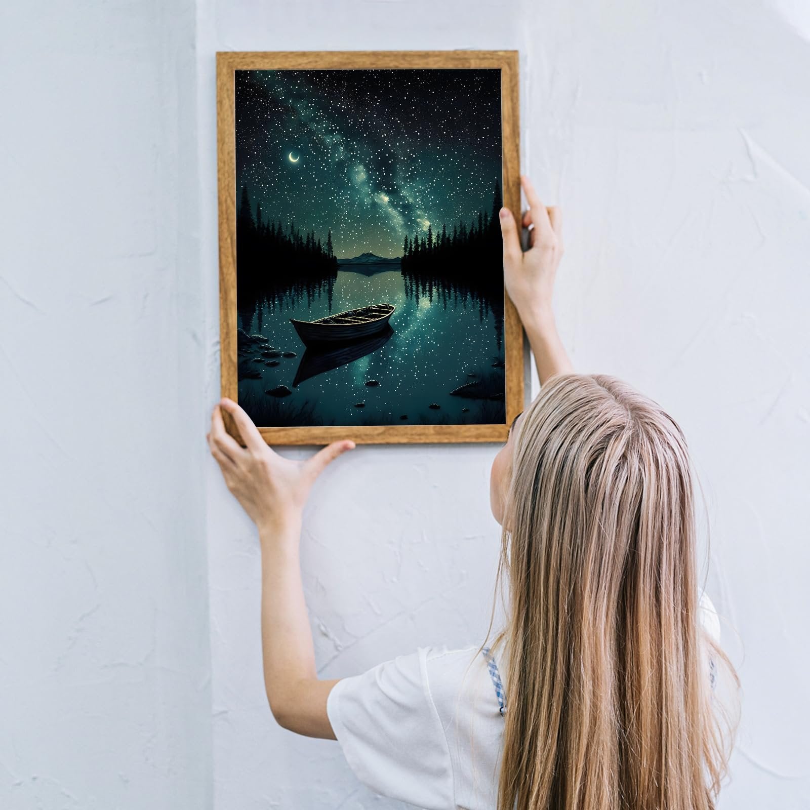 Woman hanging framed starry night canoe lake landscape diamond painting kit on wall