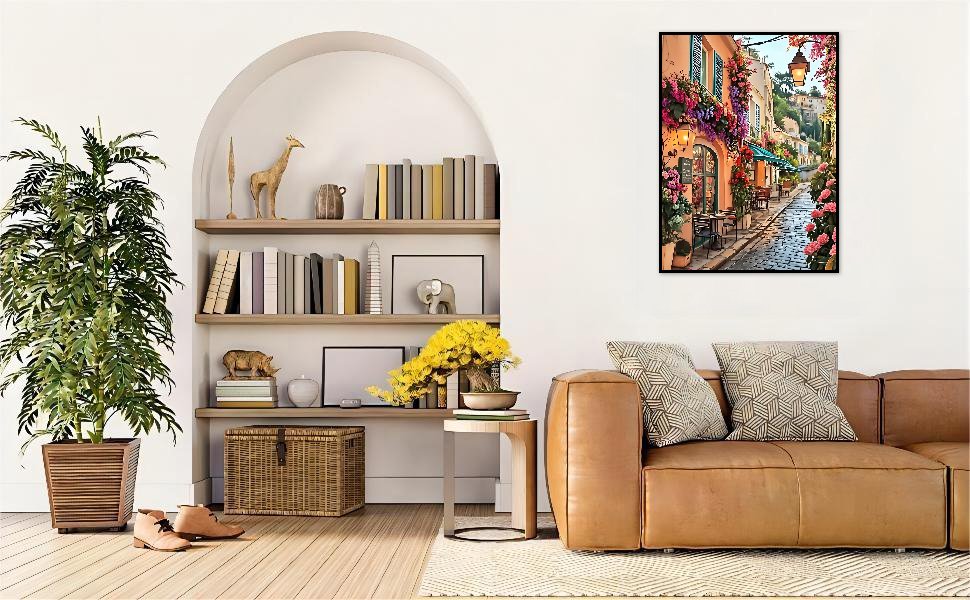 Diamond painting of a European street scene with flowers and outdoor cafe tables hanging on a wall above a sofa.