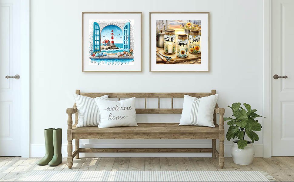 Two framed art prints hanging above a wooden bench with pillows and boots, one print shows a lighthouse scene, the other shows mason jars with flowers.