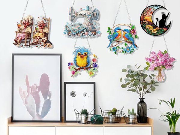 Five diamond art wall hangings displayed on a wall: two grandmas, a sewing machine, two birds, a blue bird, and a vase of lilacs.