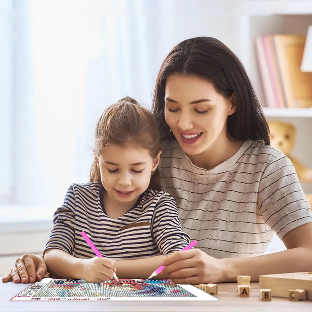 Mother and daughter doing a diamond art kit together at a table, smiling and focused on the canvas.