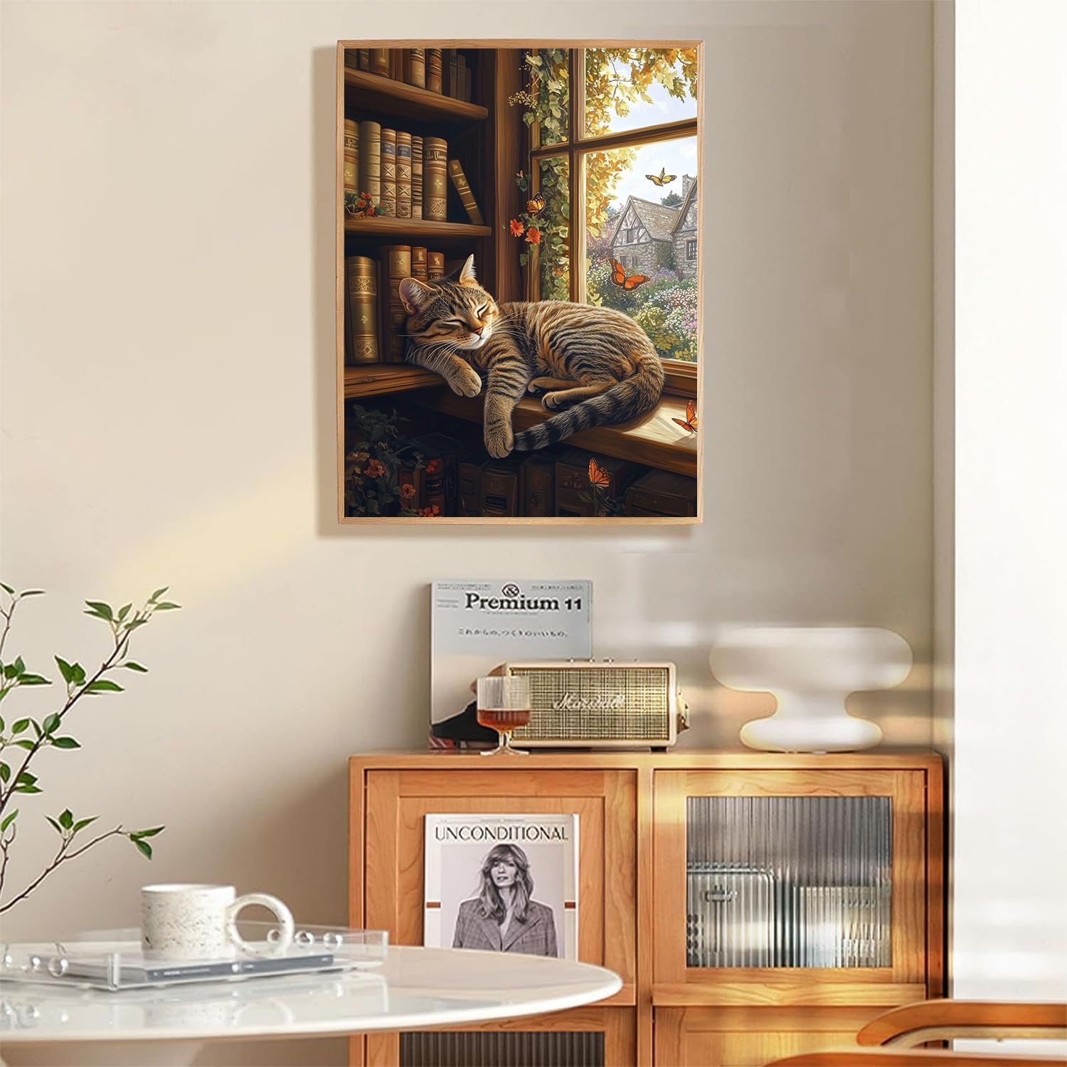 Cat sleeping on a windowsill with bookshelves and a village scene outside the window.
