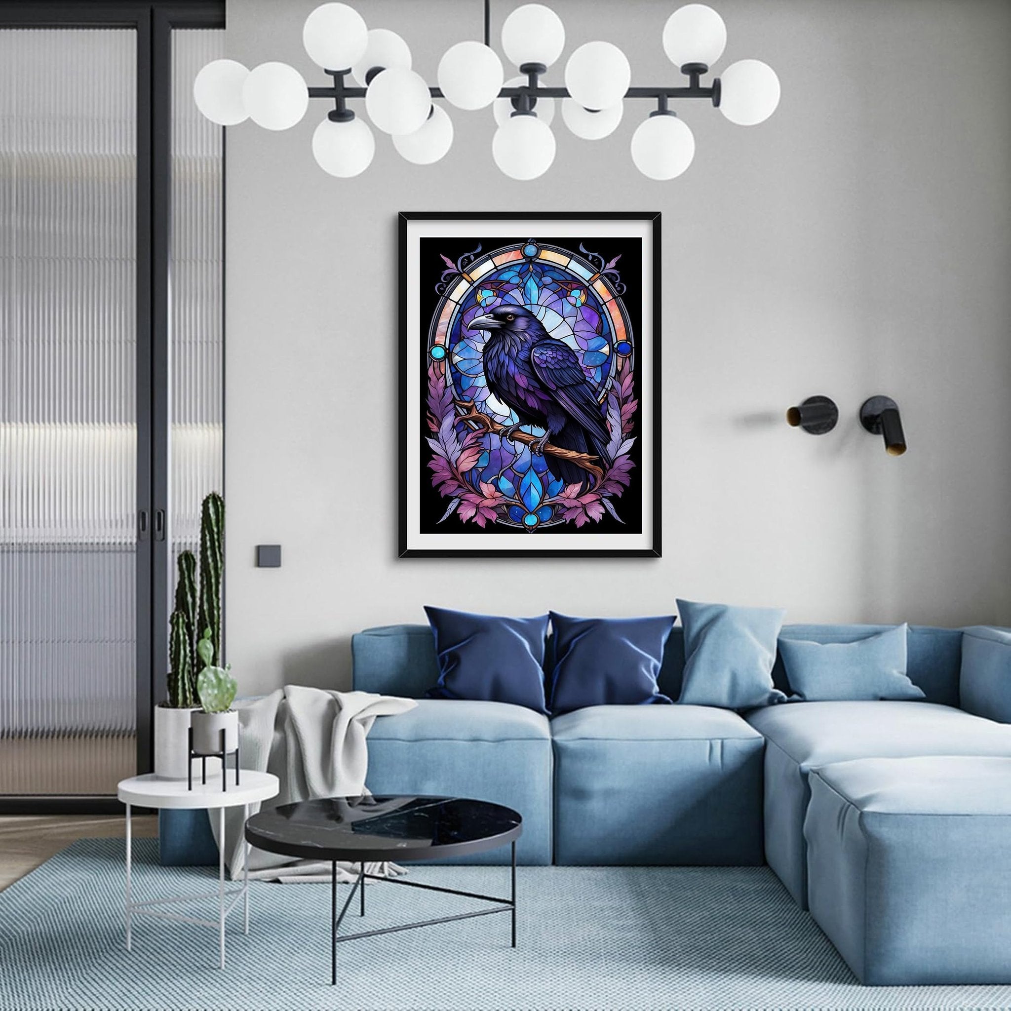 Framed diamond painting of a raven perched on a branch against a stained-glass-like background, displayed on a wall above a blue sectional sofa.