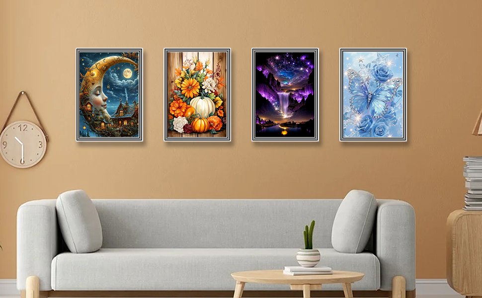 Four framed diamond paintings displayed on a wall above a sofa: a crescent moon house, a pumpkin and flower arrangement, a waterfall under a starry sky, and a blue butterfly with roses.