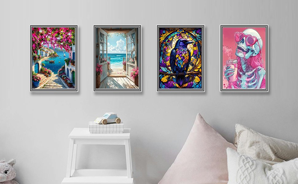 Four framed diamond paintings displayed on a wall above a white shelf, featuring a coastal village, a beach doorway, a raven, and a skeleton drinking.