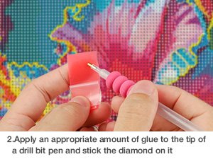 Close-up of hands applying diamond painting beads with a tool, showing a partially completed floral design.