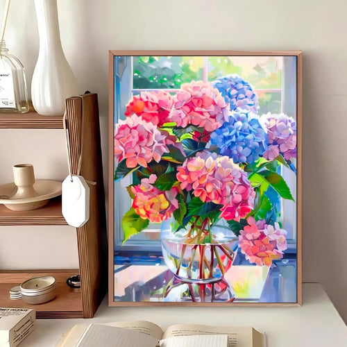 Diamond painting kit of a vase filled with pink and blue hydrangeas on a table by a window.
