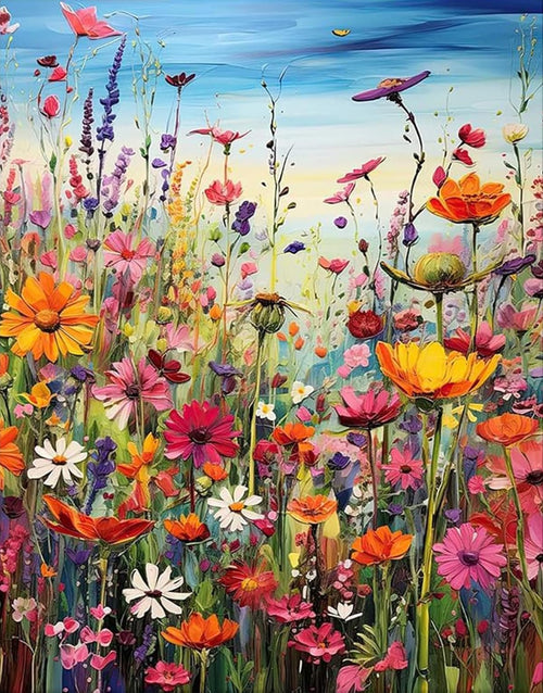 Vibrant field of wildflowers with various colorful blooms and green stems under a blue sky.