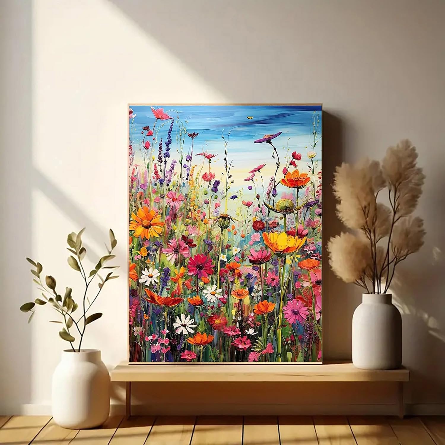 Colorful 5D diamond painting of a field of flowers with a blue sky, displayed on a shelf with vases.