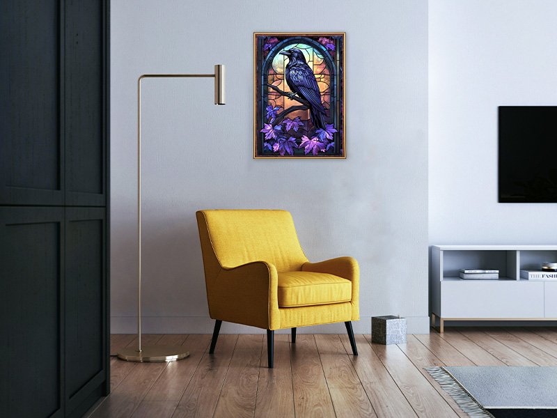 Diamond painting of a crow on a branch with purple leaves, framed and hanging on a wall above a yellow armchair.