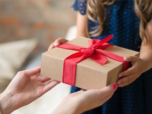 Hands exchanging a gift box tied with a red ribbon