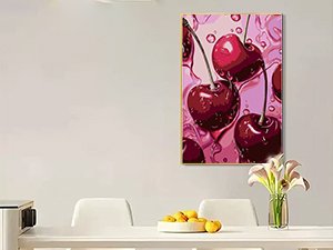 Diamond painting canvas with cherries and water droplets, framed and hanging on a wall above a table.