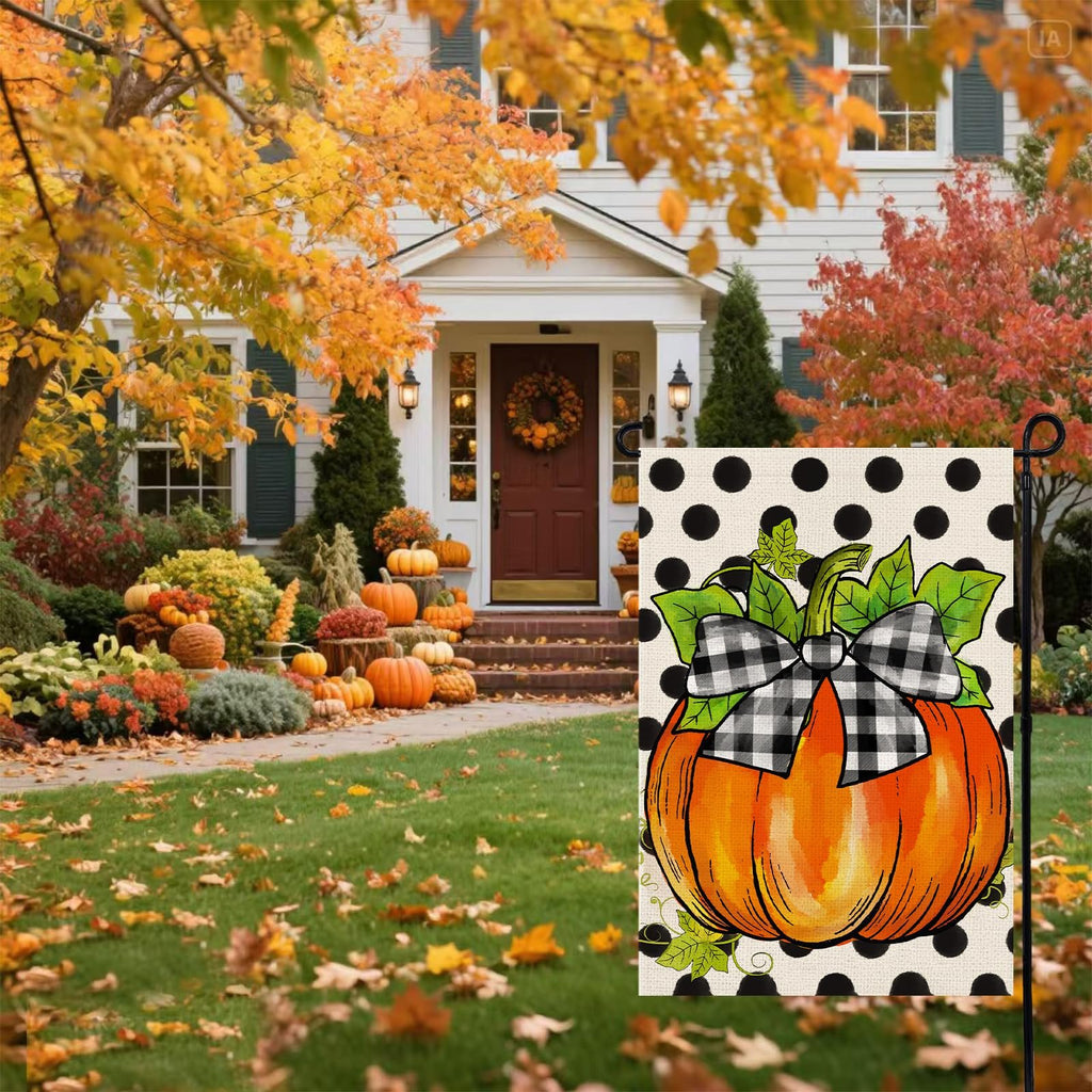 Fall garden flag with a pumpkin and buffalo plaid bow on a polka dot background, displayed in front of a house decorated for autumn.