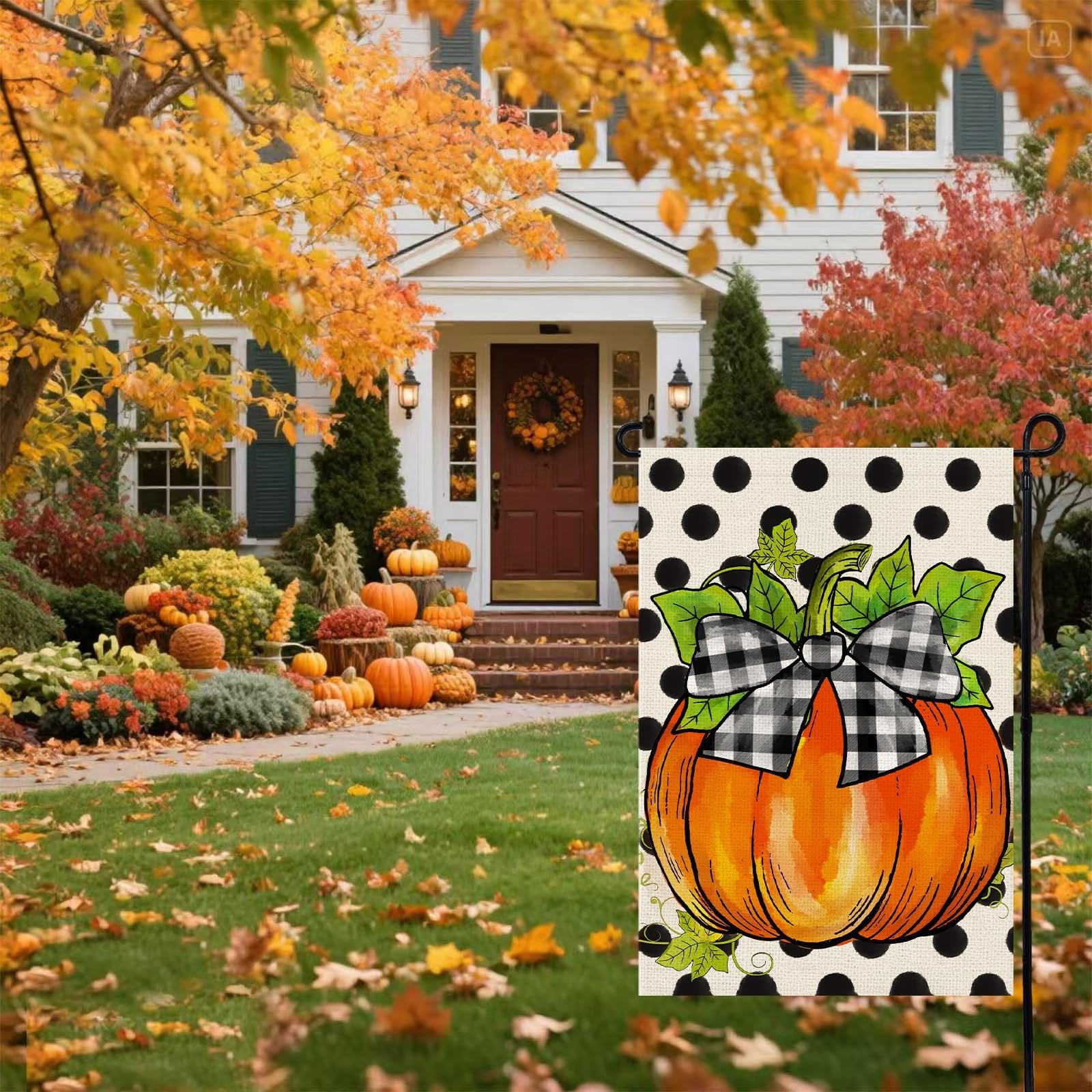 Fall garden flag with a pumpkin and buffalo plaid bow on a polka dot background, displayed in front of a house decorated for autumn.