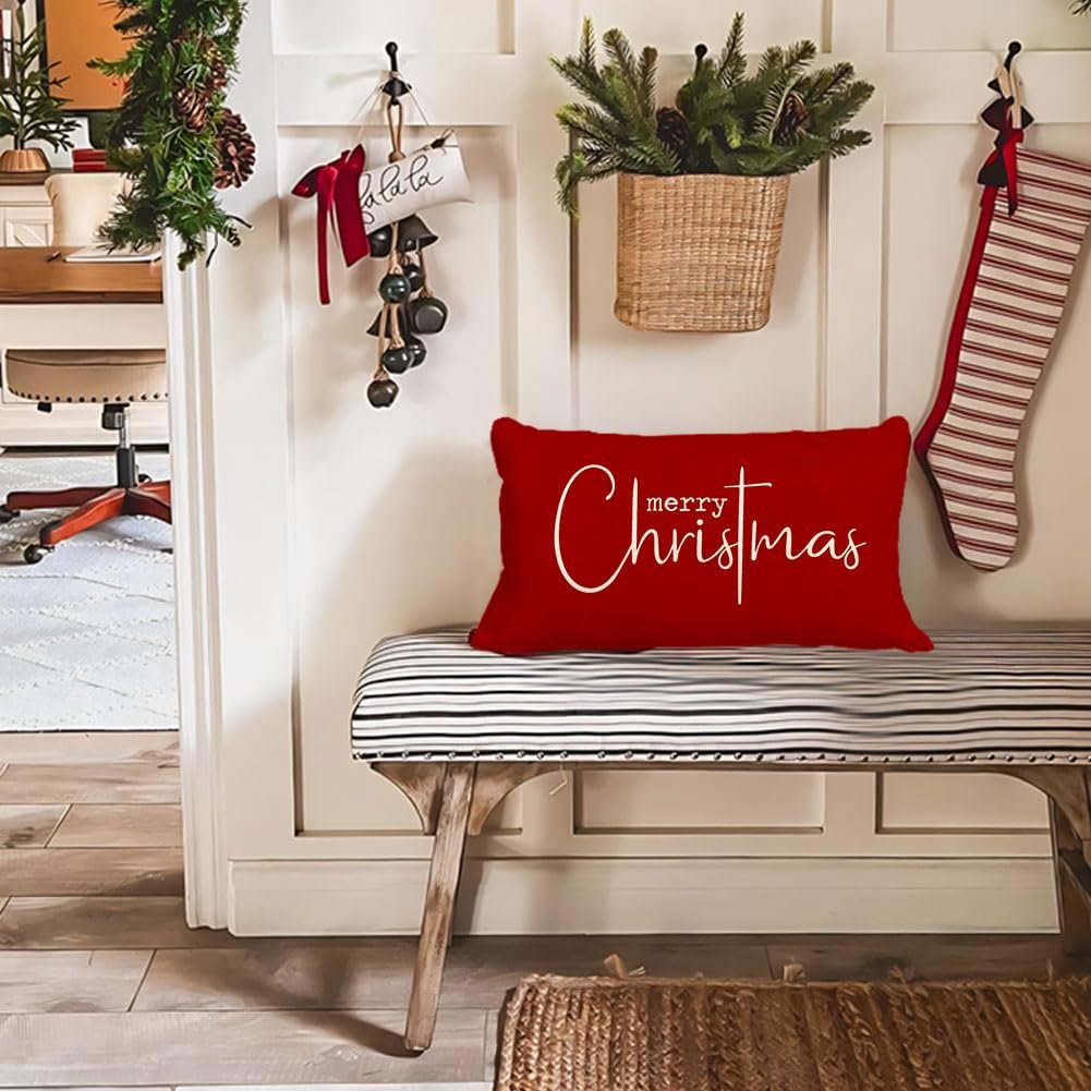 Red lumbar pillow with white 'merry Christmas' text on a striped bench in a festive entryway.