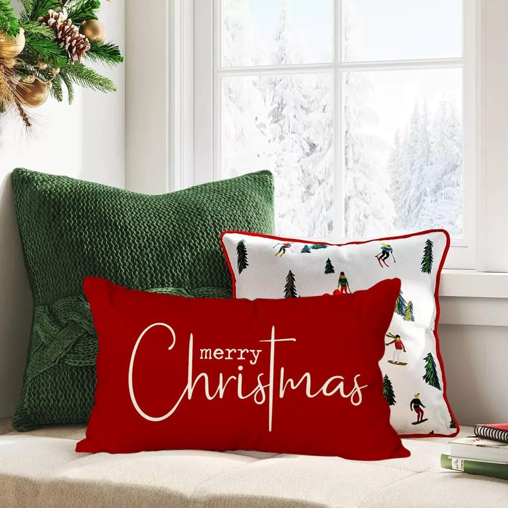 Three Christmas-themed throw pillows arranged on a window seat with a snowy forest view outside.