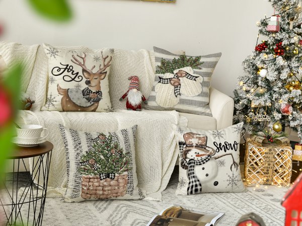 Four Christmas-themed throw pillow covers arranged on a couch and floor next to a decorated Christmas tree.