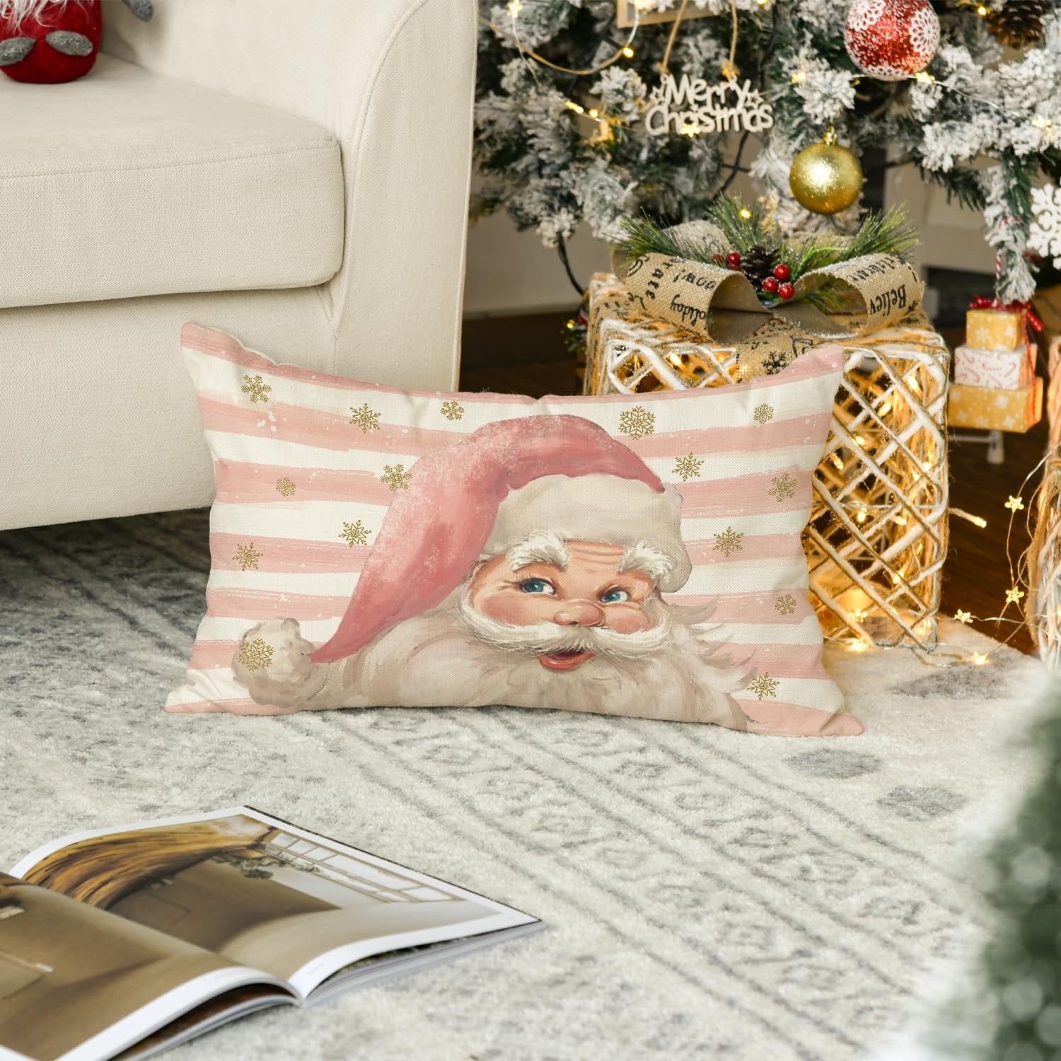 Rectangular Christmas pillow cover with Santa Claus and pink stripes, placed on a rug near a decorated Christmas tree.