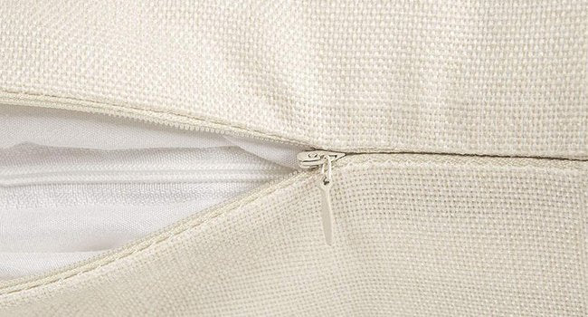 Close-up of a beige linen pillow cover showing the zipper closure and interior lining.