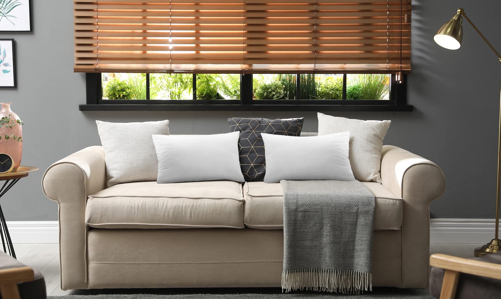 Two white pillow inserts on a beige sofa with decorative pillows and a gray throw blanket.