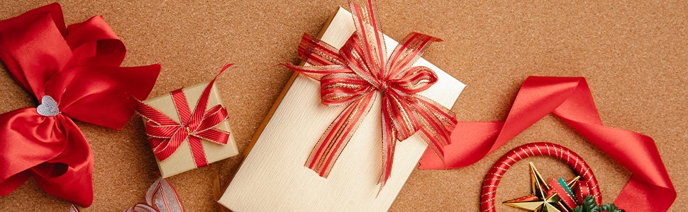 Two gift boxes with red and gold ribbons, and red ribbon accents on a cork background.