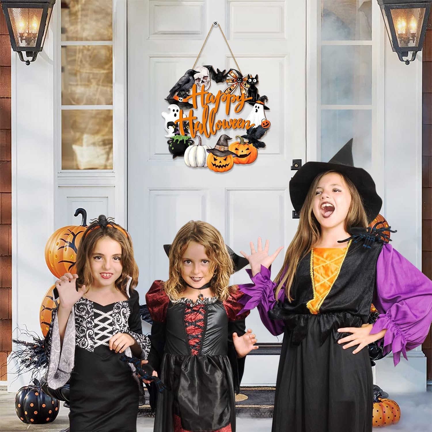 Three children in Halloween costumes posing in front of a door with a Happy Halloween wreath