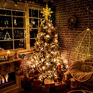 Christmas tree topper star with LED lights on a decorated Christmas tree in a cozy room setting.