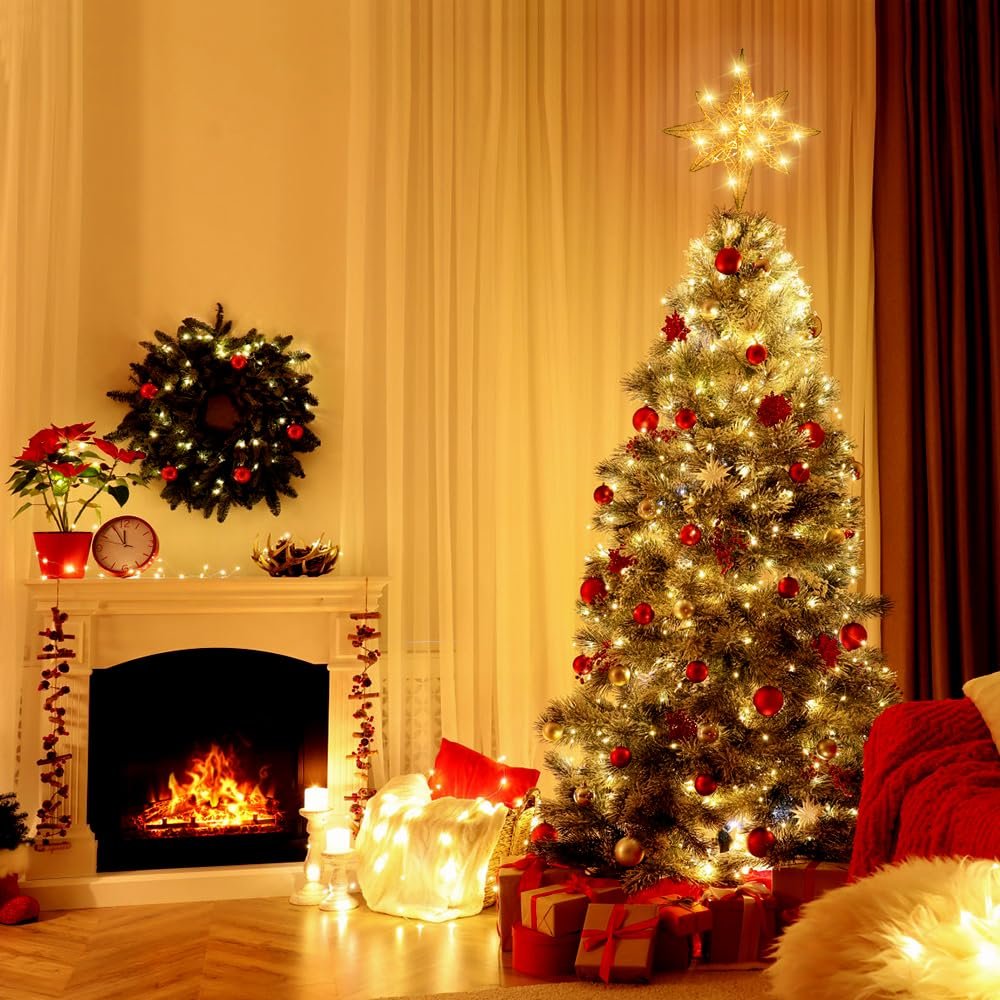 Christmas tree with gold star topper and red ornaments, next to a fireplace with a wreath.