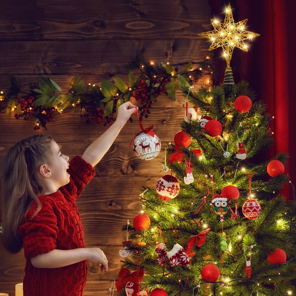 Young girl decorating a Christmas tree with a gold star topper and LED lights, hanging an ornament.