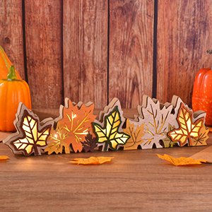 Wooden maple leaf centerpiece with integrated LED lights, set against a rustic wood background with pumpkins.