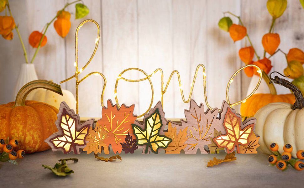 Wooden maple leaf sign spelling 'home' with LED lights, surrounded by pumpkins and fall decor.