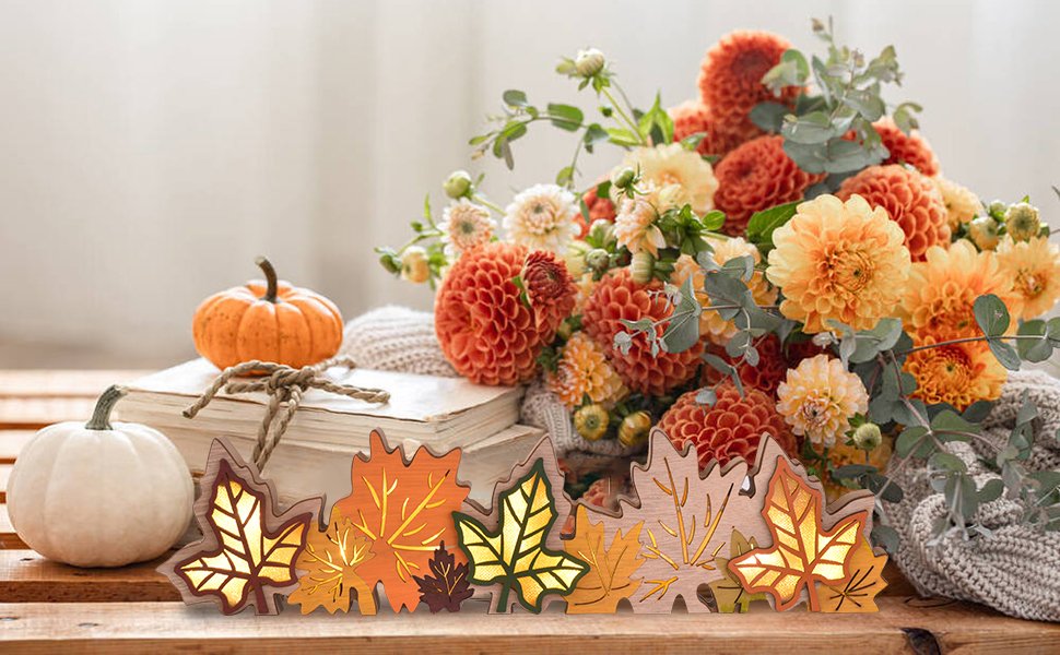 Wooden maple leaf block sign with LED lights, displayed with pumpkins and flowers on books.