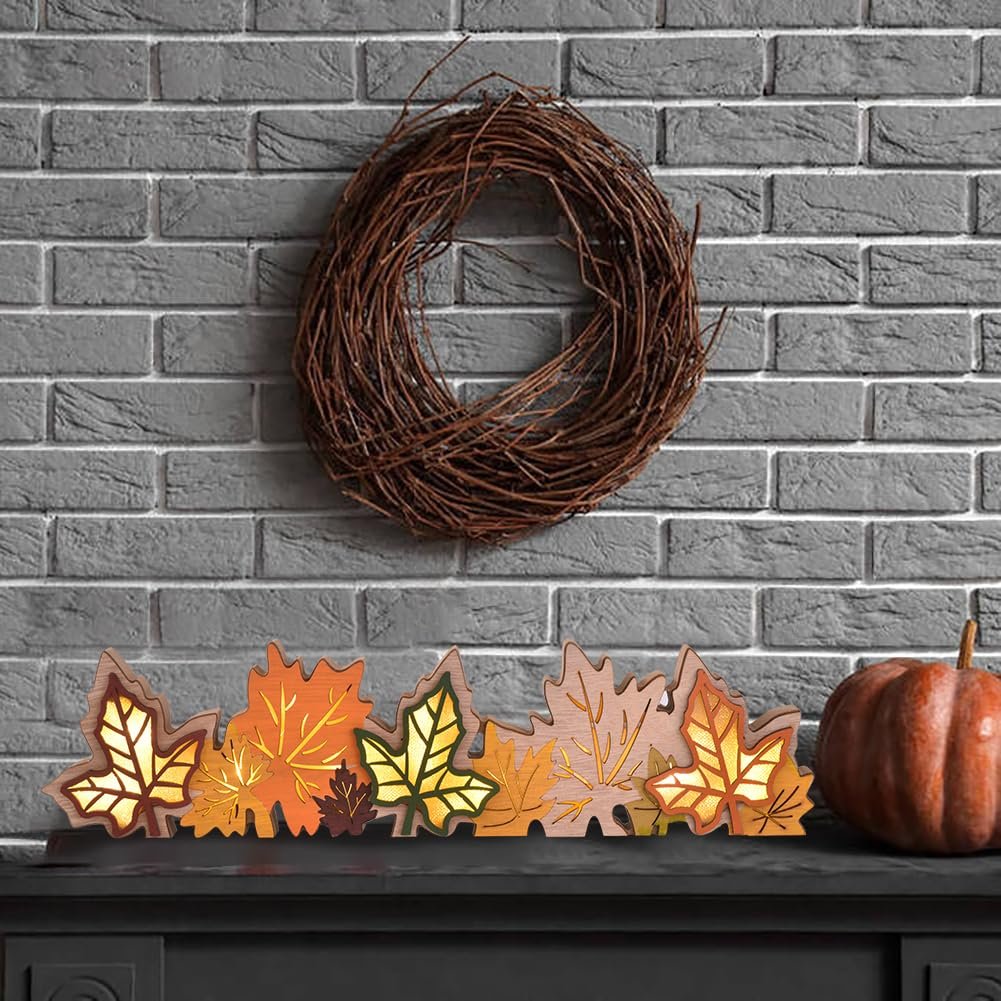 Wooden maple leaf centerpiece with LED lights on a mantelpiece with a wreath and pumpkin