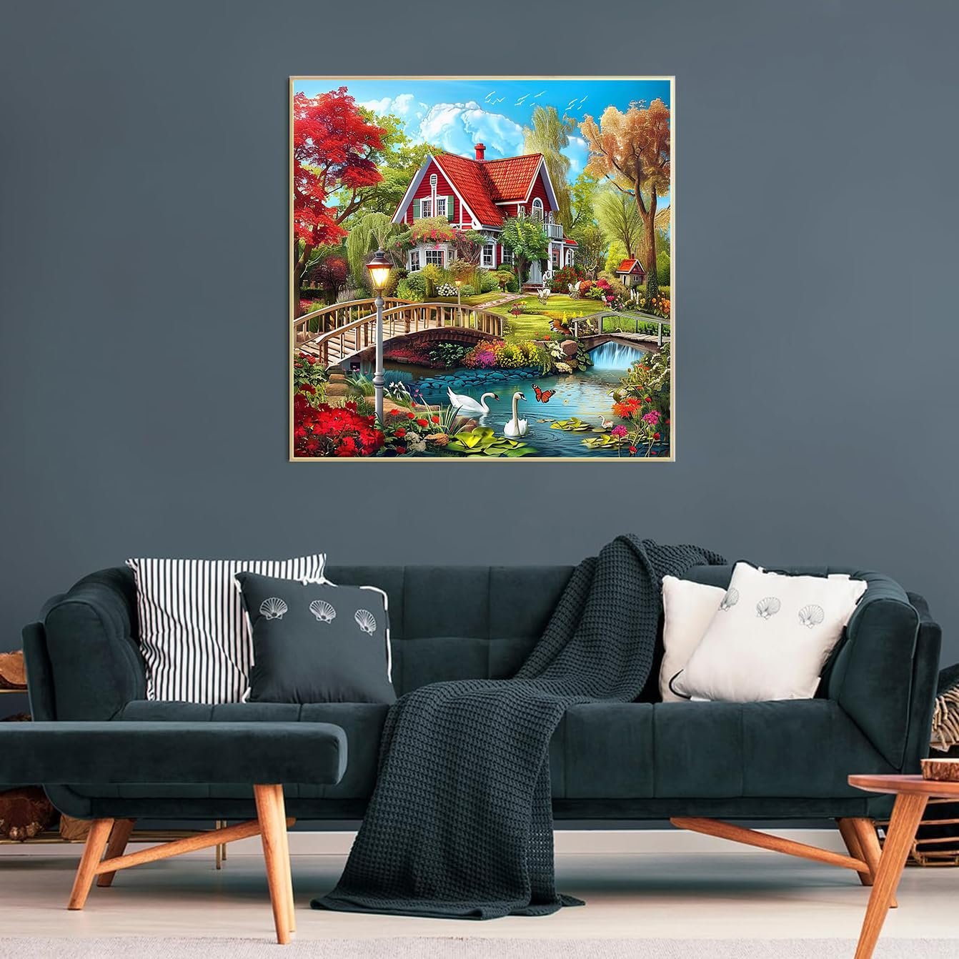 Countryside diamond painting kit featuring a red house, swans, and a bridge over a pond, displayed on a wall above a sofa.