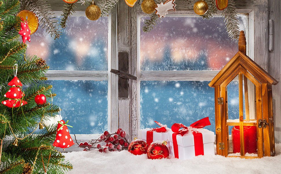 Christmas tree with ornaments and gifts by a snowy window with a wooden lantern and red candles